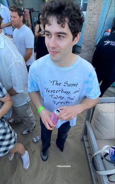 a man standing in the sand holding a drink and wearing a t - shirt that says the same yesterday