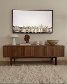 a living room with a large painting on the wall next to a coffee table and lamp