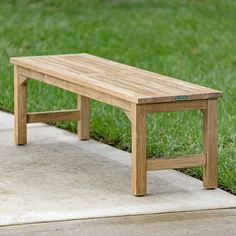 a wooden bench sitting on top of a cement slab in the grass next to green grass