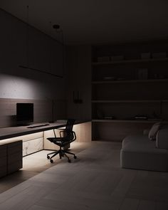 a dimly lit room with a couch, desk and television on the wall next to it