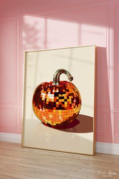 an orange mosaic pumpkin sitting on top of a hard wood floor next to a pink wall