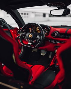 the interior of a sports car with red leather and black trim, including steering wheel