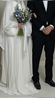 a man and woman standing next to each other in formal wear, dressed in white