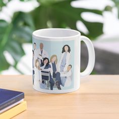 a coffee mug with an image of people on it sitting on a table next to some books