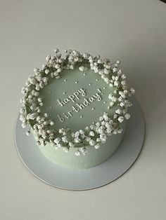 a birthday cake decorated with white flowers and the words happy birthday written in frosting