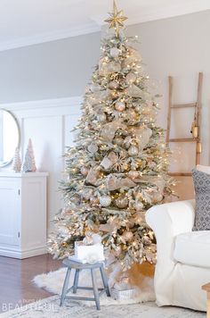 a white christmas tree in a living room with gold and silver ornaments on the top