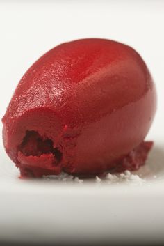 a red dessert on a white plate with sugar sprinkled all over it's surface