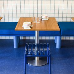 two blue benches with cups on them in a diner's dining room, next to each other