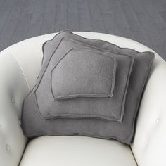 two gray pillows sitting on top of a white chair