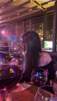 a woman sitting at a table with wine glasses