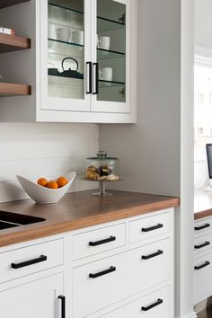 a bowl of oranges sitting on top of a kitchen counter next to a sink