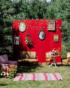 an outdoor area with furniture and pictures on the wall, in front of some trees