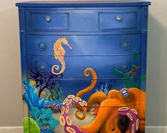 a dresser painted with an octopus and seahorse on the bottom, next to a wall that says bring the beach to you