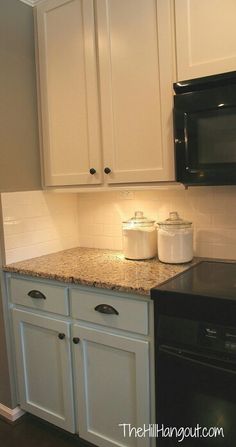 a kitchen with white cabinets and black appliances