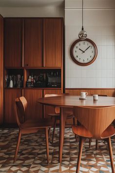 a table with two chairs and a clock on the wall above it in a kitchen