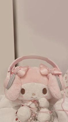 a pink hello kitty purse with headphones attached to it and a teddy bear on the bed