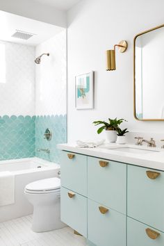 the bathroom is decorated in white and blue with gold accents on the vanity, toilet, tub