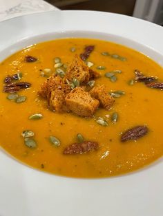 a white bowl filled with carrot soup and croutons