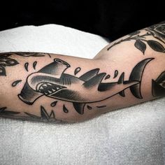 a man's arm with a shark tattoo on it and an arrow in the middle