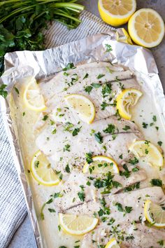 baked fish with lemons and herbs on foil