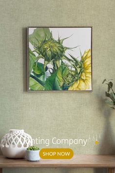 a painting hanging on the wall next to a vase with flowers and plants in it