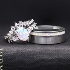 two wedding rings with white opal and diamond accents on top of each other in front of a black background