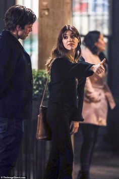 a man and woman standing next to each other in front of a building at night