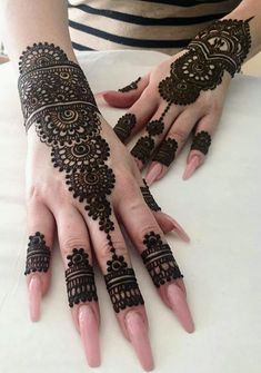 two hands with henna tattoos on them sitting on a white tablecloth in front of a woman's face