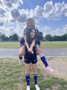 two girls in soccer uniforms are hugging each other on the field with their arms around one another