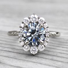 an engagement ring with a large blue diamond surrounded by smaller round diamonds on top of it