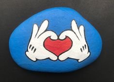 two hands holding a heart painted on a rock