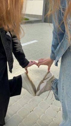 two girls are holding hands and walking down the street together, with their shoes off