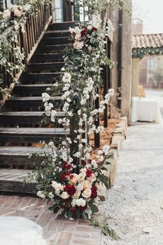 an outdoor ceremony with flowers and greenery on the steps leading up to the wedding venue