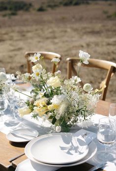 the table is set with white plates and flowers