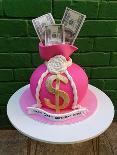 a pink vase with money in it on top of a table next to a green brick wall