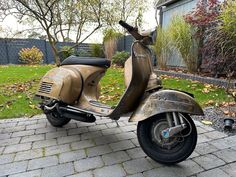 an old scooter is parked in front of a house on a brick walkway