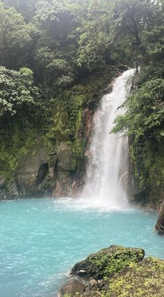 there is a waterfall and blue water in the middle of this area with trees on both sides