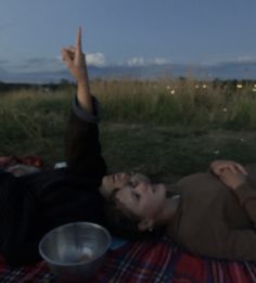 a woman laying on top of a blanket next to a metal bowl