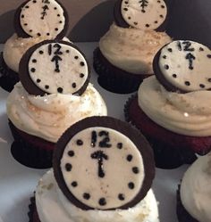 cupcakes with white frosting and black decorations on them are arranged in the shape of clocks