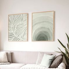 two paintings hang on the wall above a couch