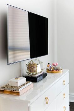 a flat screen tv sitting on top of a white dresser