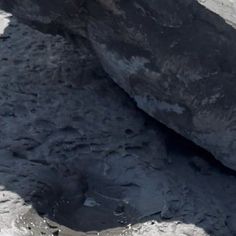 an aerial view of a large rock in the middle of some snow covered ground with water coming out of it