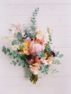 a bouquet of flowers sitting on top of a wooden table next to a white wall