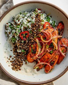 a white bowl filled with meat, rice and veggies on top of a table