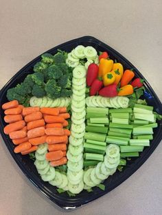 a black tray filled with lots of different types of veggies on top of each other