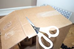 a pair of scissors cutting through a cardboard box