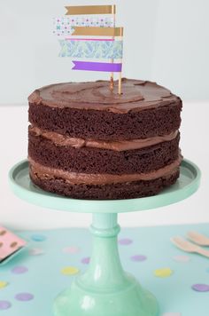 a chocolate cake sitting on top of a blue plate with a flag sticking out of it