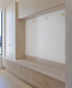 an empty room with white walls and wooden shelves on the wall next to a window