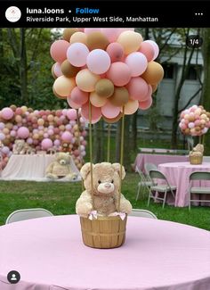 a teddy bear sitting on top of a basket with balloons in the shape of flowers