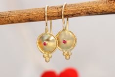 "Exquisite, antique-style very small ruby and 14k, 18k or 22k solid gold hook drop earrings. These amazing drop earrings have a decorated domed disc and a tiny red ruby set in the middle of it. At the bottom of the disc on each earring, there are three gold dots that add character to these boho earrings. These earrings are elaborate and delicate but still very noticeable. They have a unique eye-catching boho look that will go with and upgrade any outfit. Ruby is the birthstone of July and is con Boho Wedding Ring, 22k Gold Earrings, Gold Bridal Earrings, 18k Gold Earrings, Yellow Gold Wedding Band, Solid Gold Earrings, Gold Dots, Ruby Earrings, Ruby Jewelry